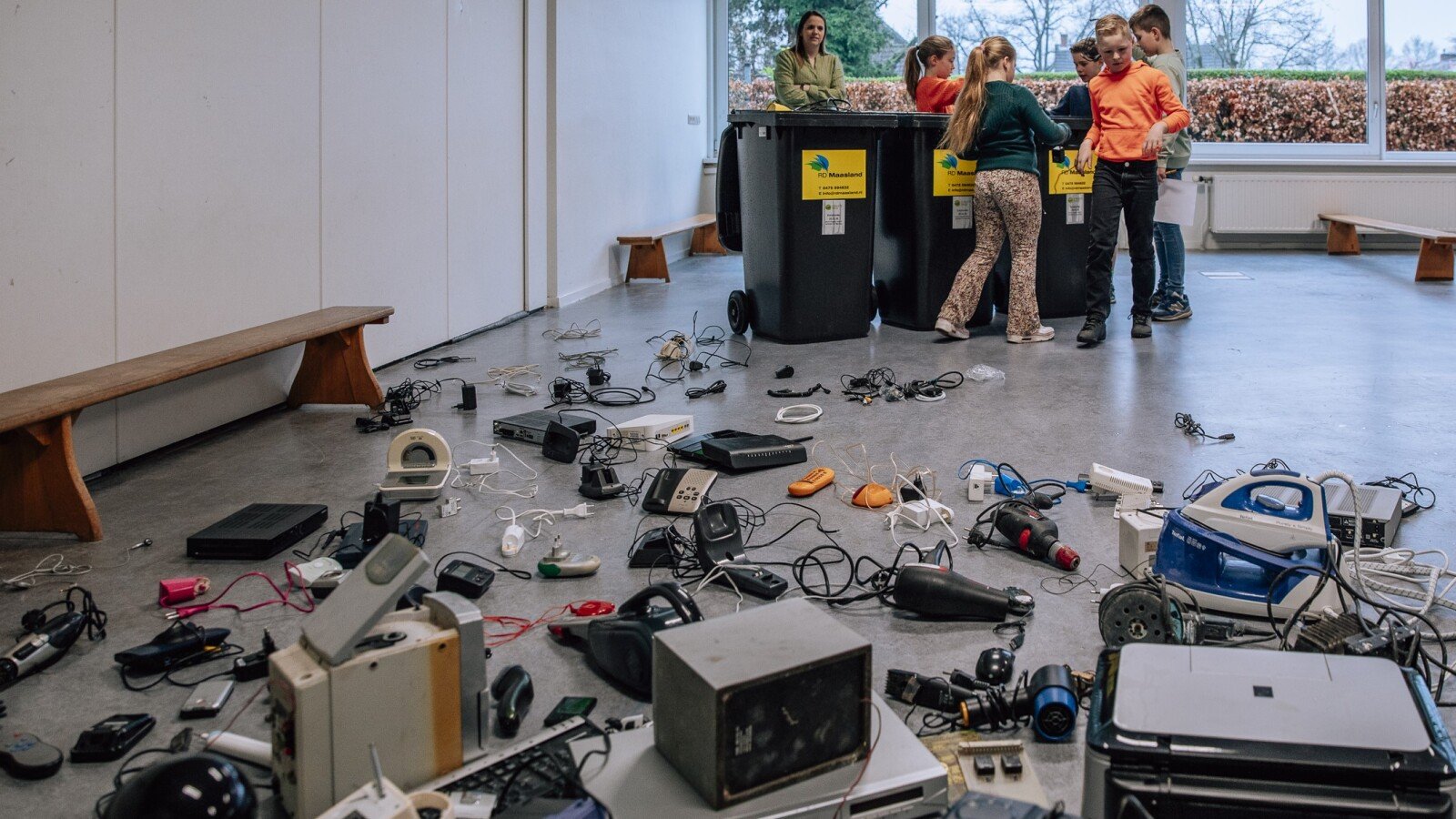 Elektrische apparaten liggen gesorteerd op de vloer tijdens een e-waste-inzameling op een school